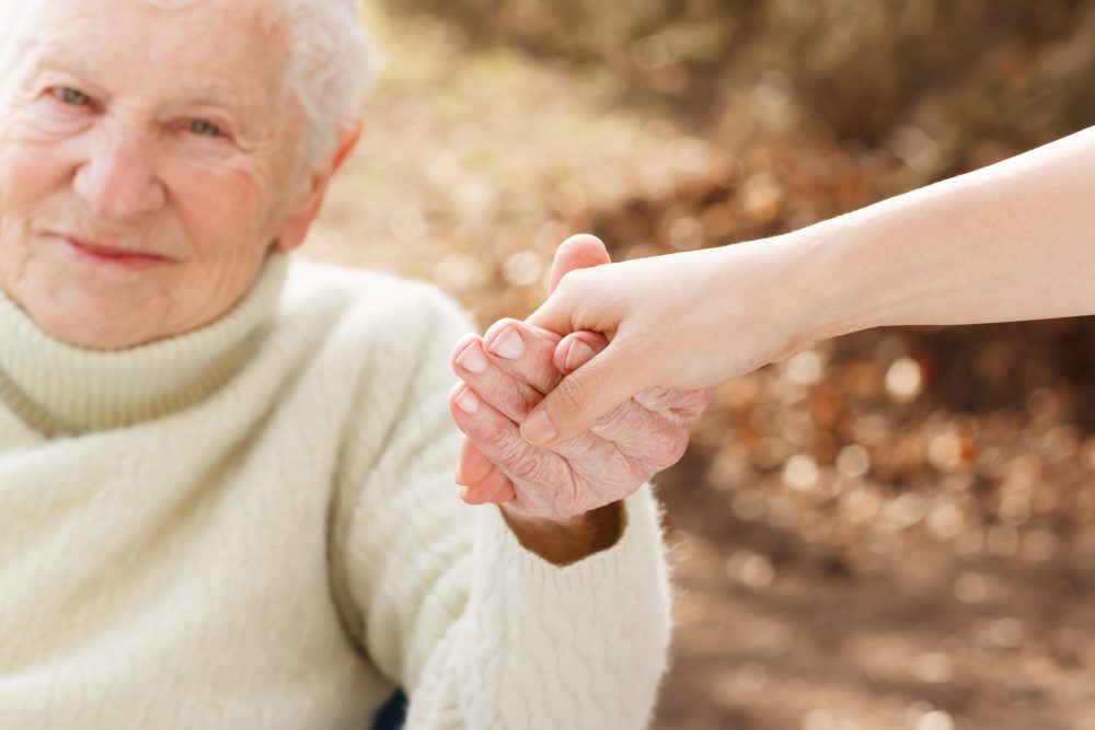 A smiling elderly woman holding hands with a companion home care worker from MasterPeace Home Health Care in Mattapoisett, MA