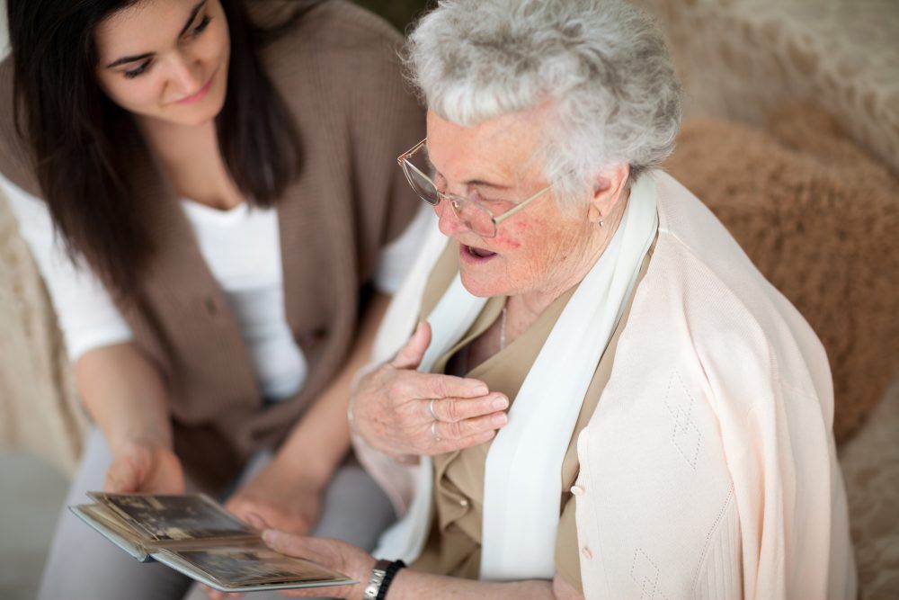 A companion home care worker looking at photos with a member of MasterPeace Home Health Care in Mattapoisett, MA