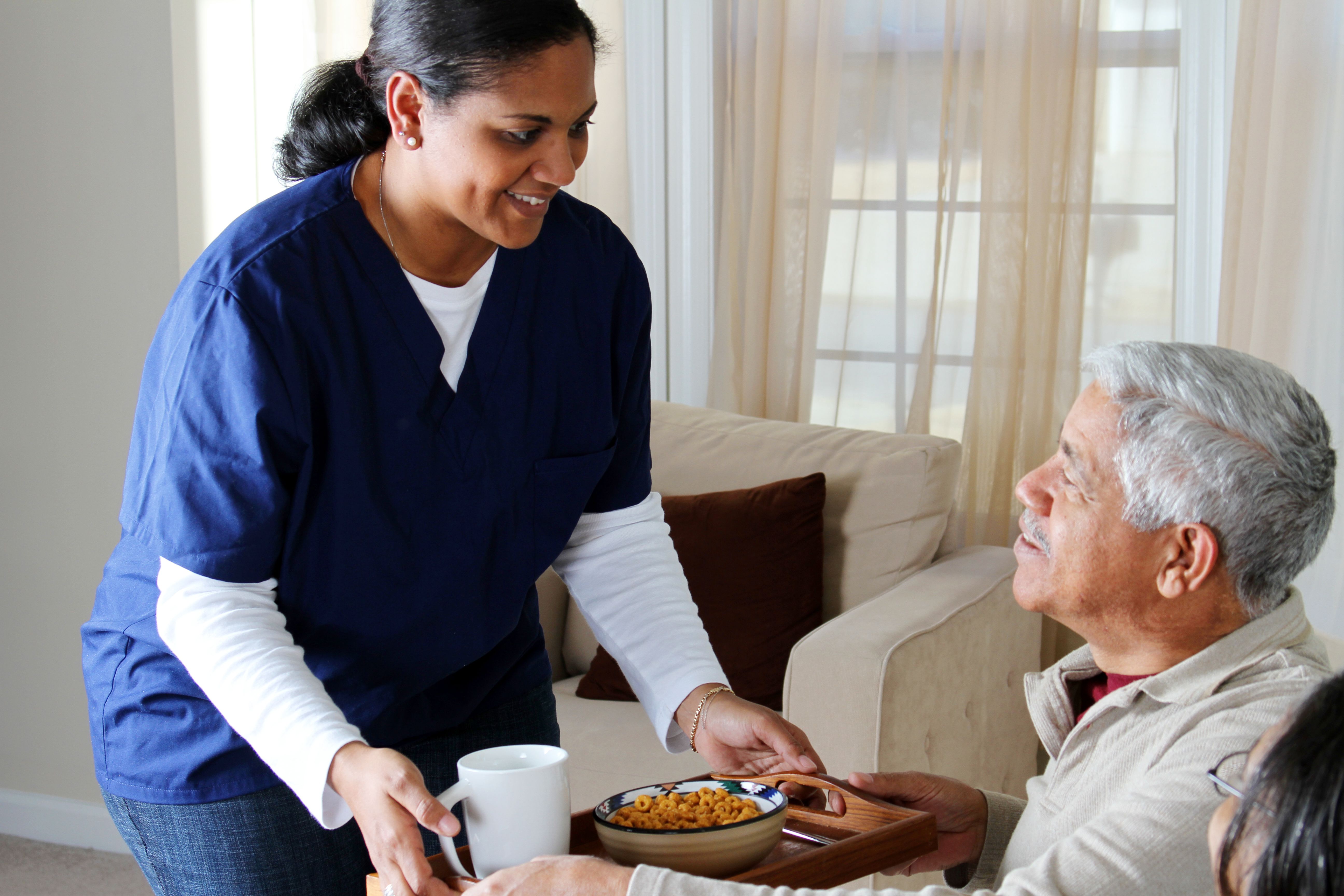 A nurse serving a meal to an elderly persona as part of the companion home care program at MasterPeace Home Health Care in Mattapoisett, MA